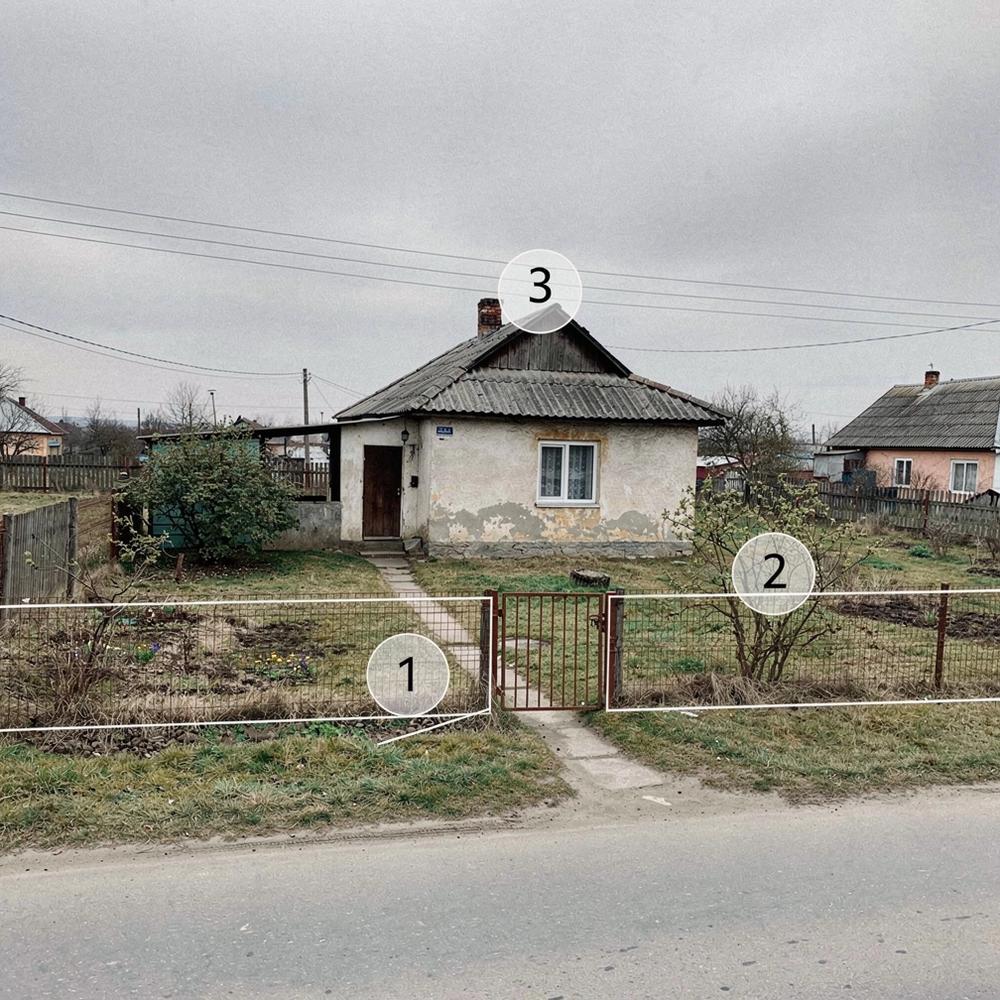 Village house on a fenced plot seen from the road, with numbered markers placed over the plot outline